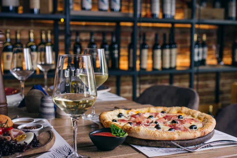 Pizza with prosciutto and olives with wine in a restaurant