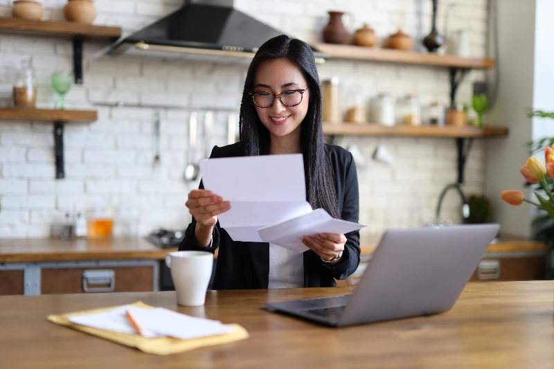 businesswoman happily reads a finance letter at her desk managing paperwork in her office
